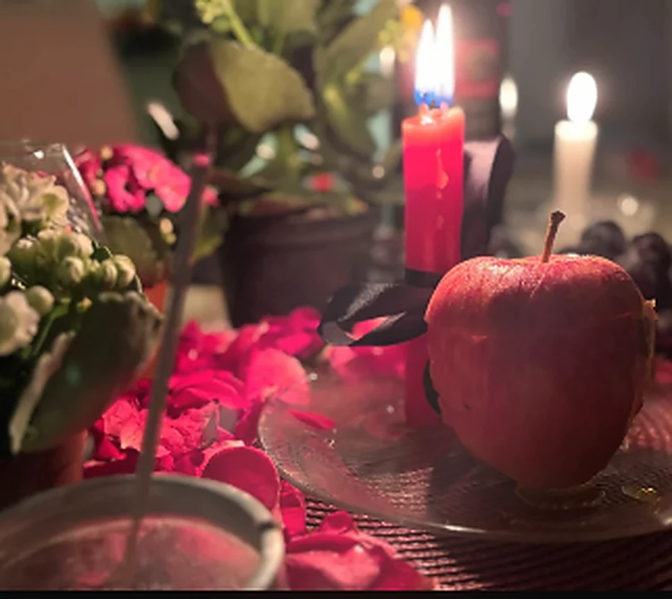 Velas, pétalas vermelhas e uma maçã em um ritual de amor